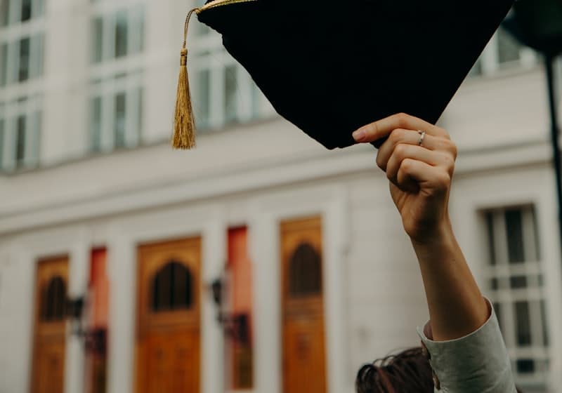 Mũ tốt nghiệp giơ cao trước toà nhà trường đại học